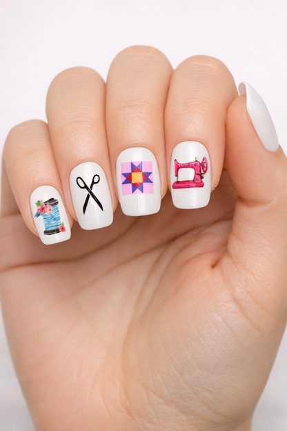 Nail art with sewing-themed designs on a white background